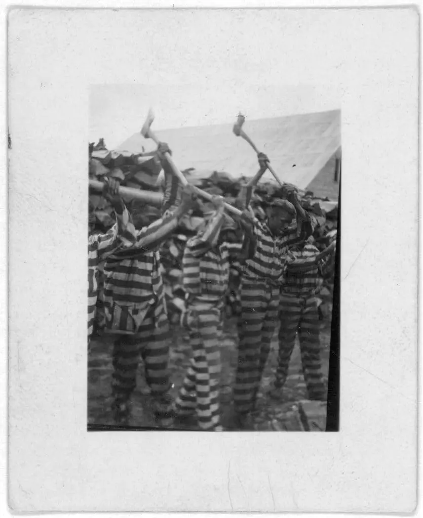 African American convicts working with axes and singing in woodyard, Reed Camp, South Carolina